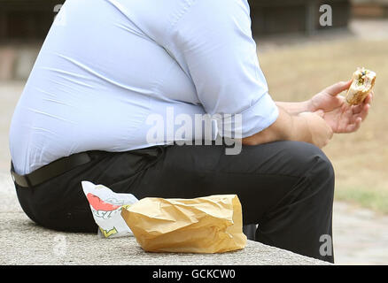 Un uomo in sovrappeso mangia cibo veloce. Il GPS e altri professionisti della salute dovrebbero dire alle persone che sono grassi piuttosto che obesi, ha detto oggi un ministro della salute. Foto Stock