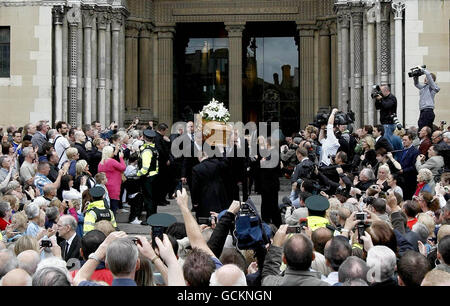 La folla guarda avanti mentre la bara di Alex Higgins viene portata dalla cattedrale di St Anne, Belfast, dove ha avuto luogo il suo servizio funerario.