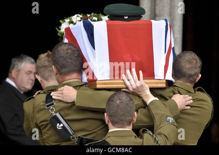 Pallbearers dai Fucili spalla la bandiera dell'Unione ha drappeggiato la bara del maggiore Josh Bowman mentre è condotto nella cattedrale di Salisbury dove un servizio funerale è tenuto in suo onore. Foto Stock