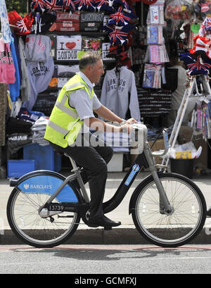 Un uomo guida una delle nuove biciclette a noleggio, lanciata oggi dal sindaco di Londra Boris Johnson, sul ponte di Westminster a Londra. Foto Stock