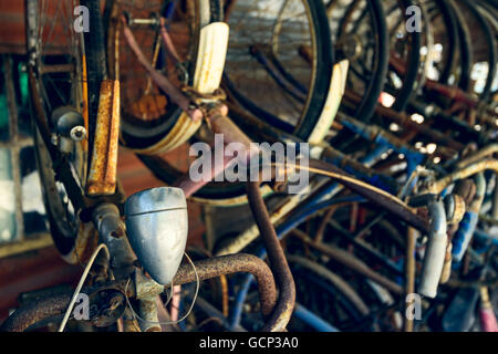 Vecchio arrugginito biciclette stack in una pila nel capannone Foto Stock