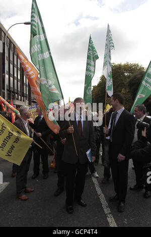 Il leader del Sinn Fein, Gerry Adams, detiene una bandiera mentre i sindacati irlandesi protestano contro tagli e salvataggi per le banche, al di fuori della Leinster House di Dublino. Foto Stock