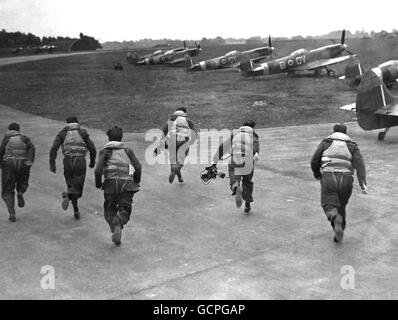 L'aerodromo di Biggin Hill, Kent, campo d'aviazione di prima linea durante la Battaglia di Gran Bretagna, la scena di una ripetizione di uno 'scramble' da parte di alcuni degli assi da combattimento del 1940. Questa volta, tuttavia, non c'erano Messerchmitts nel cielo, e le telecamere erano lì per trasmettere la scena come parte della Battaglia di Gran Bretagna anniversario celebrazioni. L'immagine mostra: Al segnale di 'scramble' i piloti si sono precipitare verso il loro aereo, come hanno fatto nei giorni frenetici della battaglia di Gran Bretagna. La scena a Biggin Hill il 14 settembre 1946. Foto Stock