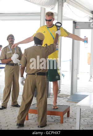 I membri della squadra australiana passano attraverso i controlli di sicurezza all'entrata al Villaggio degli atleti a Nuova Delhi, India. Foto Stock