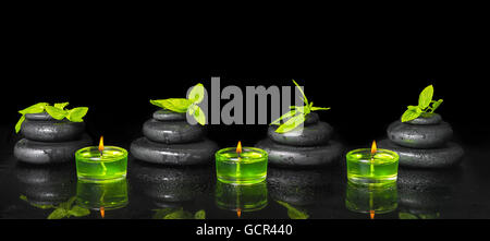 Spa sfondo della piramide zen pietre di basalto con gocce d'acqua, menta verde e candele su nero, close up Foto Stock