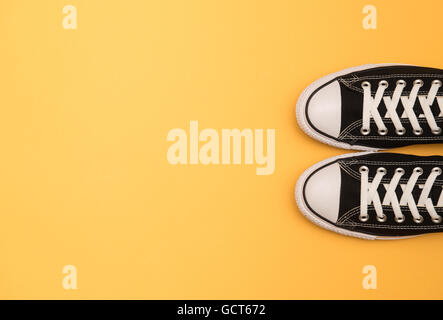 Sneakers nero su sfondo giallo Foto Stock