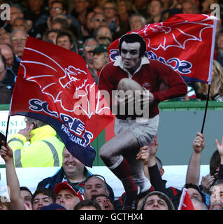 Llanelli Scarlets tifosi mostrare il loro sostegno negli stand come Presentano un taglio di cartone di Llanelli ex e Galles Fly mezzo Phil Bennett Foto Stock