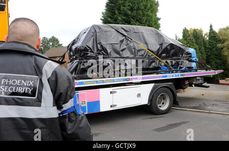 I resti bruciati della Range Rover cromata di Andrew Carroll vengono rimossi dall'esterno della casa del capitano Kevin Nolan. Foto Stock