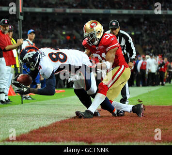 Denver Broncos Brandon Lloyd (a sinistra) si aggancia ai punteggi di palla un touchdown sotto la pressione di San Francisco 49ers Will James durante la partita NFL al Wembley Stadium, Londra. Foto Stock