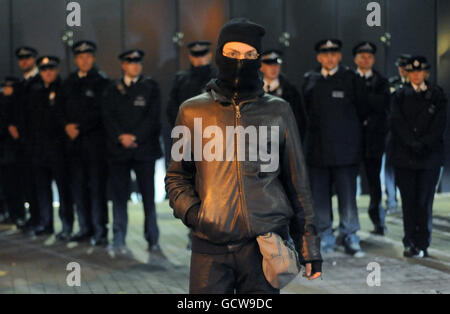 Un dimostratore mascherato è visto di fronte ai funzionari di polizia mentre gli studenti organizzano una protesta al di fuori del King's Place, uffici del giornale Guardiano e Osservatore, dove il Vice primo Ministro sta dando la conferenza annuale Hugo Young nel centro di Londra. Foto Stock