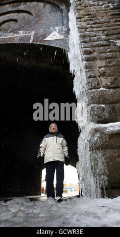 Un membro del pubblico cammina sotto una colonna di ghiaccio di 15 piedi, formata da acqua che fuoriesce da un ponte di canale in Spouthouse Lane, Hampstead, Birmingham. Foto Stock