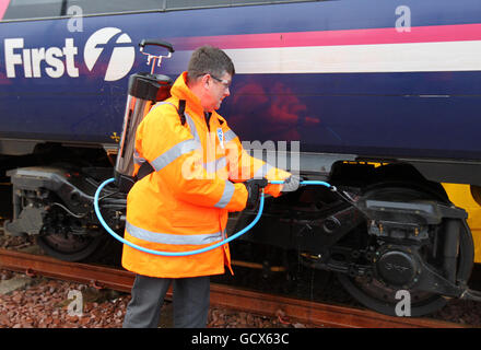 Il nuovo ministro dei Trasporti scozzese Keith Brown utilizza lo spray "Kill Frost" per lo sbrinamento che impedisce e facilita la rimozione del ghiaccio dal carro di un treno durante una visita al deposito Eastfield di ScotRail a Glasgow. Foto Stock