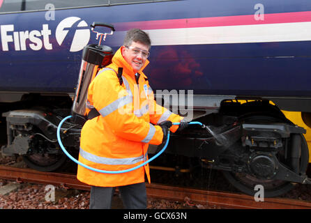 Il nuovo ministro dei Trasporti scozzese Keith Brown utilizza lo spray "Kill Frost" per lo sbrinamento che impedisce e facilita la rimozione del ghiaccio dal carro di un treno durante una visita al deposito Eastfield di ScotRail a Glasgow. Foto Stock