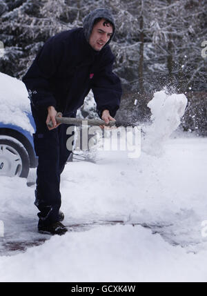 Un uomo libera la neve dal suo viaggio a Edimburgo mentre la neve e le condizioni ghiacciate colpiscono la Scozia centrale. Foto Stock