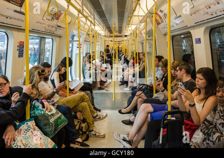 I passeggeri a bordo di un treno della District Line della metropolitana di Londra. Foto Stock