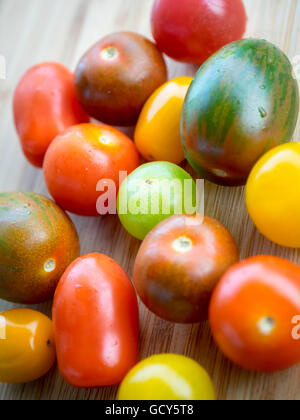 Una bella e coloratissima serie di estate varietà di pomodoro su una superficie di bambù. Foto Stock