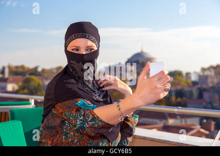 Signora in nero Hijab tenendo il telefono Foto Stock