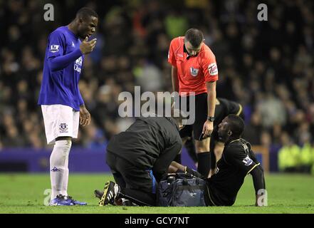 Victor Anichebe di Everton (a sinistra) continua la sua discussione con Wigan Athletic's. Steve Gohouri come riceve il trattamento per una ferita Foto Stock