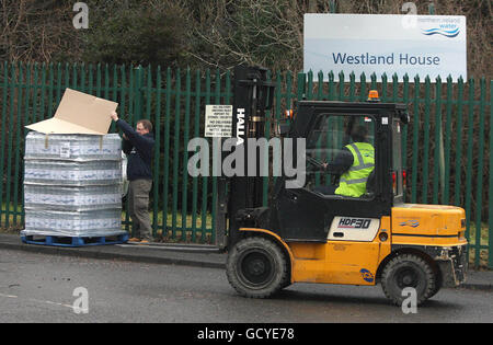 Un dipendente dell'Irlanda del Nord perde acqua da un pallet di acqua potabile fornito dall'esecutivo scozzese al di fuori della sede centrale dell'azienda a North Belfast. Foto Stock