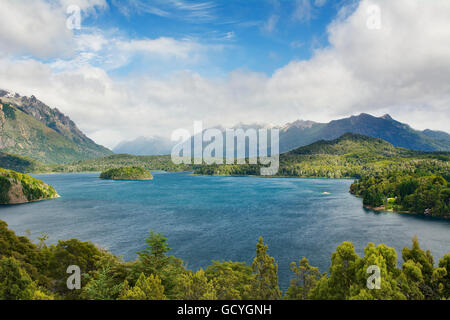 Grande lago di montagna con montagne innevate della distanza con le nuvole creando una luce interessante sul paesaggio; Argentina Foto Stock