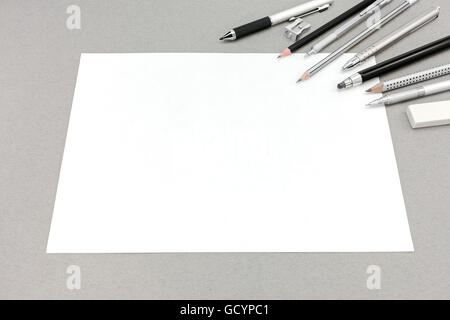 Foglio di carta bianco e accessori da disegno su grigio carta riciclata in background Foto Stock