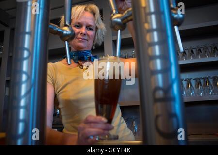 Cameriere di donna con la birra sparatutto Gruut all'interno della fabbrica di birra in Gentse Stadsbrouwerij, Gand, Belgio. Foto Stock