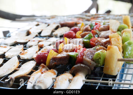 Pollo shish kebab sulla griglia per il barbecue in salsa su spiedini con pomodori e peperoni. gamberi e funghi eringii grill. Foto Stock