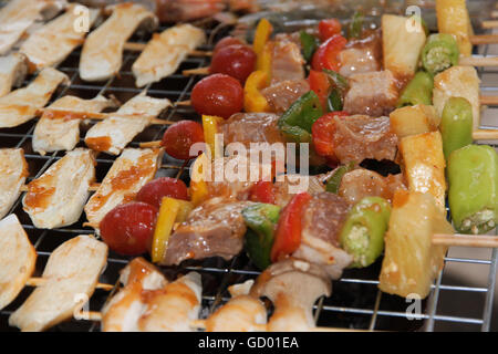 Pollo shish kebab sulla griglia per il barbecue in salsa su spiedini con pomodori e peperoni. gamberi e funghi eringii grill. Foto Stock