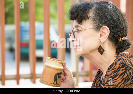 Primo piano lato Visualizza il profilo verticale, nonna godendo di tazza di bevanda, isolato sfondo all'aperto Foto Stock