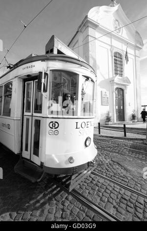 I tram a Lisbona con la luce del sole i modelli di colata e ombre sulla pavimentazione e i binari del tram