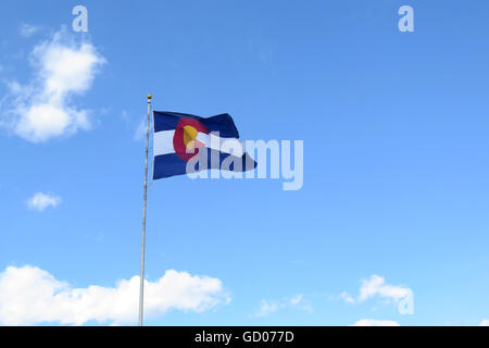 Il Colorado onde bandiera orgogliosamente contro un cielo azzurro con poche nuvole a distanza Foto Stock