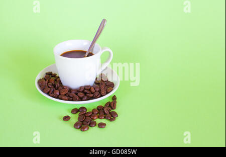 Caffè espresso e caffè in grani pastello su sfondo verde. Foto Stock