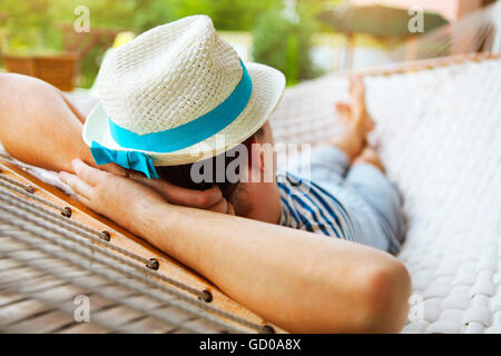 Tempo pigro. Uomo in hat in una amaca in un giorno di estate Foto Stock