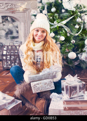 Felice giovane donna con il Natale presente nelle sue mani dall'albero di Natale Foto Stock