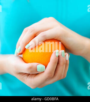 Le belle mani di una donna con il turchese french manicure holding arancione Foto Stock