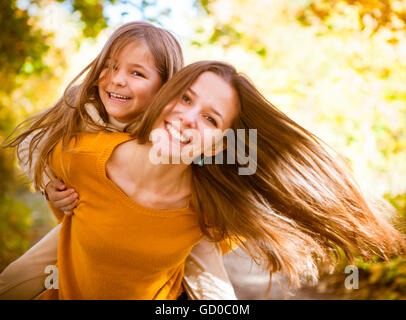 Due sorelle allegro giocando nel parco di giorno di autunno caldo Foto Stock