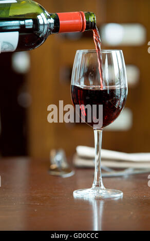 Il vino rosso è versata in un bicchiere di vino. Foto Stock