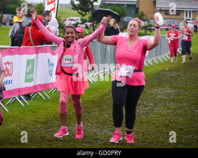 Portsmouth, Hampshire, Regno Unito. Il 10 luglio 2016. Due amici attraversare la linea del traguardo Holding Hands, alla fine della corsa per la vita. La gara per la vita è un evento di beneficenza in cui le femmine completare un 10Km o 5 Km di correre in aiuto del cancro ricerca. Credito: simon evans/Alamy Live News Foto Stock