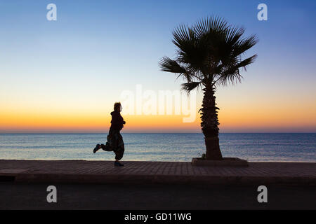 Giovane donna di jogging sul lungomare rendendo Fitness di mattina Foto Stock