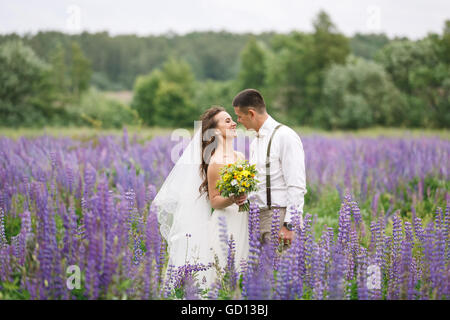 Felice matrimonio giovane costeggiata nel campo di lupino Foto Stock