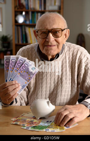 Uomo vecchio, senior, 92 anni, con il porcellino salvadanaio e banconote in euro Foto Stock