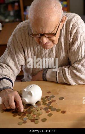 Uomo vecchio, senior, 92 anni, con il porcellino salvadanaio e monete in euro Foto Stock