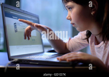 Ragazza, 10 anni, con il computer portatile, su Facebook pagina web Foto Stock