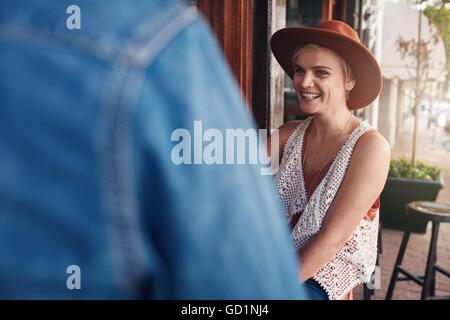 Sorridente giovane donna seduta a un coffee shop con il suo amico. I giovani seduti ad un tavolo del bar. Foto Stock