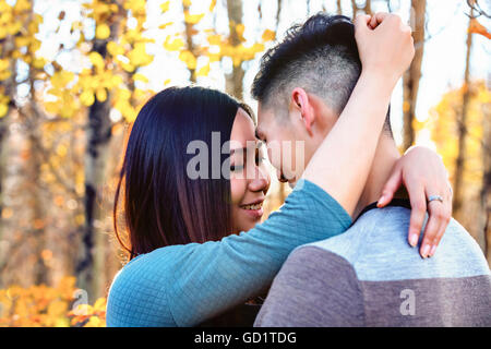 Una giovane coppia asiatica godendo Di Un tempo romantico insieme all'aperto in Un Parco in autunno e abbracciandosi nel calore della luce del sole... Foto Stock