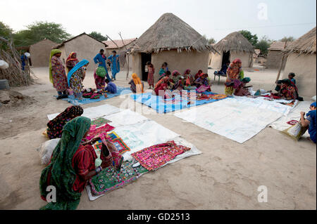 Pathan le donne del villaggio che mostra ricami tradizionali di fronte di fango e paglia case tribali, Jarawali, Kutch, Gujarat, India Foto Stock