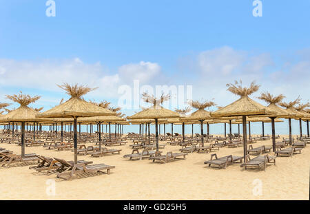 Spiaggia con ombrelloni di paglia e lettini in legno. Foto Stock