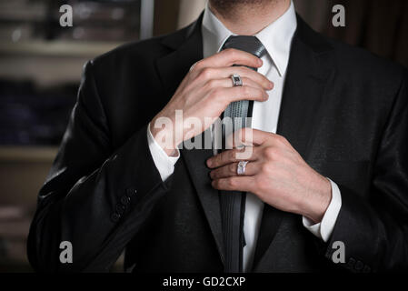 Giovane uomo d affari che fissa il suo tirante Foto Stock