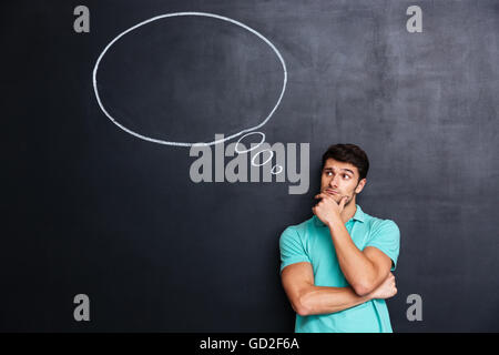 Malinconici attraente giovane con bolla di pensiero su sfondo blackboard Foto Stock
