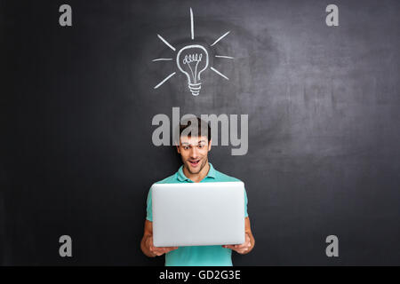 Felice giovane uomo hanno un'idea su lavagna sfondo disegnato con lampadina Foto Stock